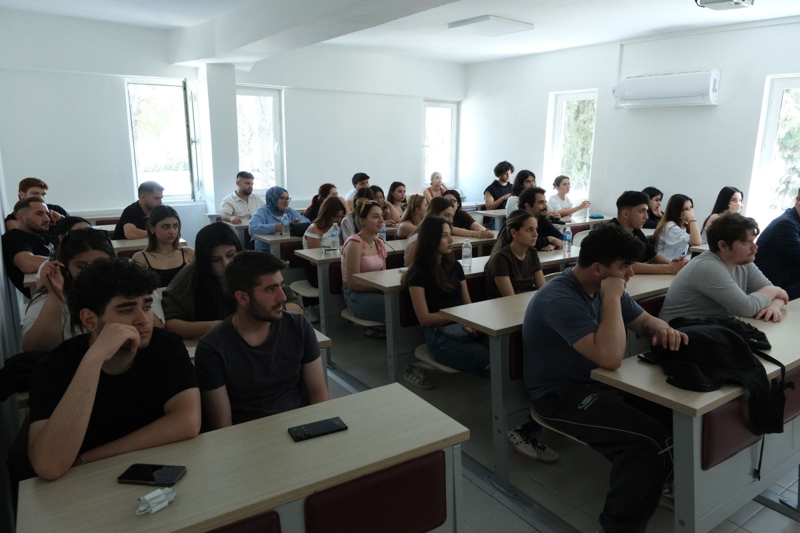 Öğrenciler, sınıf ortamında düzenlenen etkinlikte konuşmacının sunumunu dikkatle dinlemektedir.